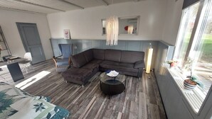 A modern living room with a sectional sofa, a glass coffee table, and a dining area with a table and chairs. - Vacation home directly on the Lagan near Markaryd (Markaryd)