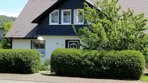A two-story house with a dark roof, white walls, and a number '35' on the side. - Apartment 'Marianne' with Private Terrace and Wi-Fi (Olsberg)