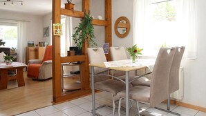 A dining area with a wooden partition, a table with chairs, a potted plant, and a mirror on the wall. - Apartment 'Marianne' with Private Terrace and Wi-Fi (Olsberg)