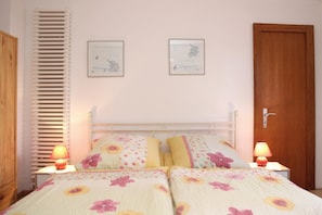 Une chambre à coucher avec un lit, deux lampes de chevet, une porte en bois et deux tableaux encadrés accrochés au mur.