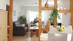 A room with a wooden dining table, a sofa, and a wooden cabinet. - Apartment 'Marianne' with Private Terrace and Wi-Fi (Olsberg)