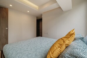 A bedroom with a bed, a wooden door, and a closet. - Brand New 2 BR Condo in Reforma - Queen Beds (Mexico City)
