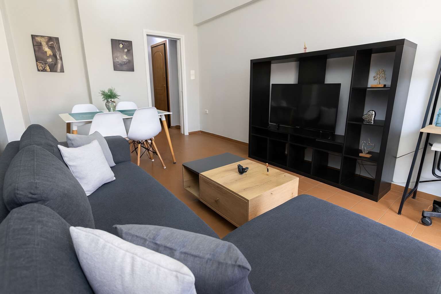 Un soggiorno moderno con un divano grigio, un tavolino, una TV e una libreria.