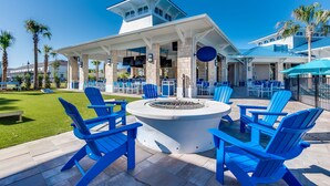 An outdoor seating area with blue Adirondack chairs and a circular fire pit. - Upstay 7BR Resort Home w Private Pool Near Disney (Davenport)