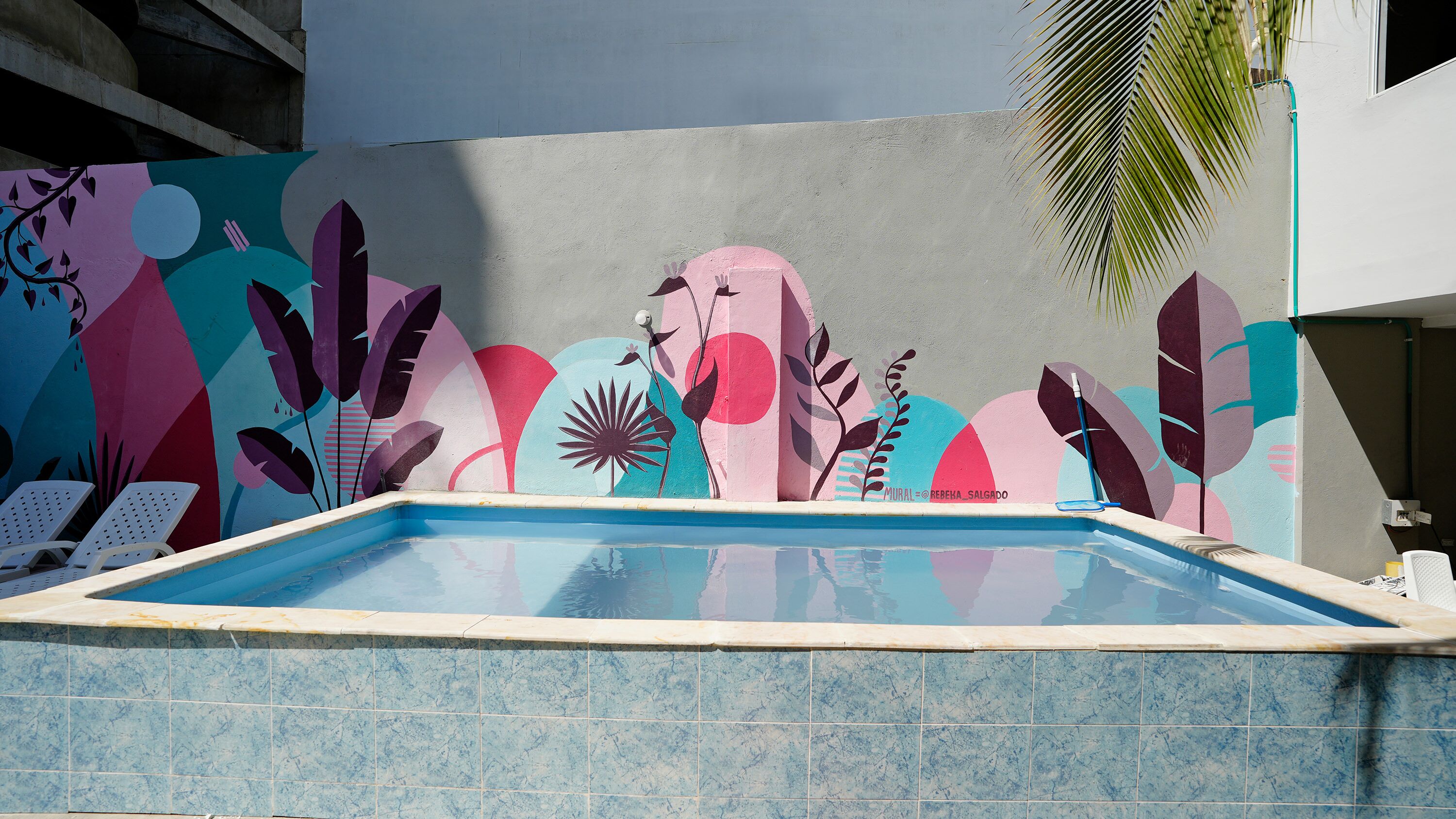 A swimming pool with a colorful mural on the adjacent wall.