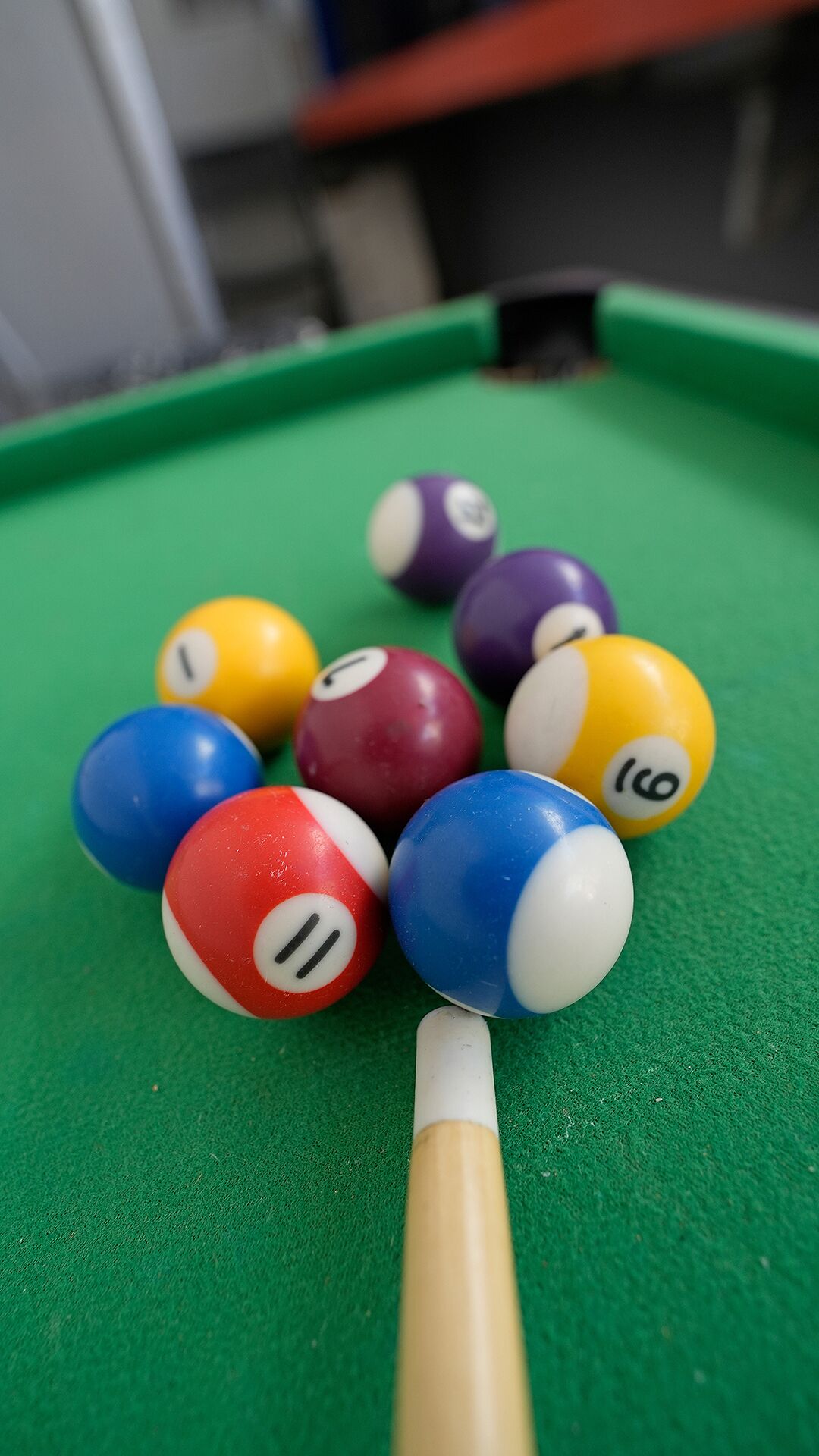 A pool table with various colored balls and a cue stick.