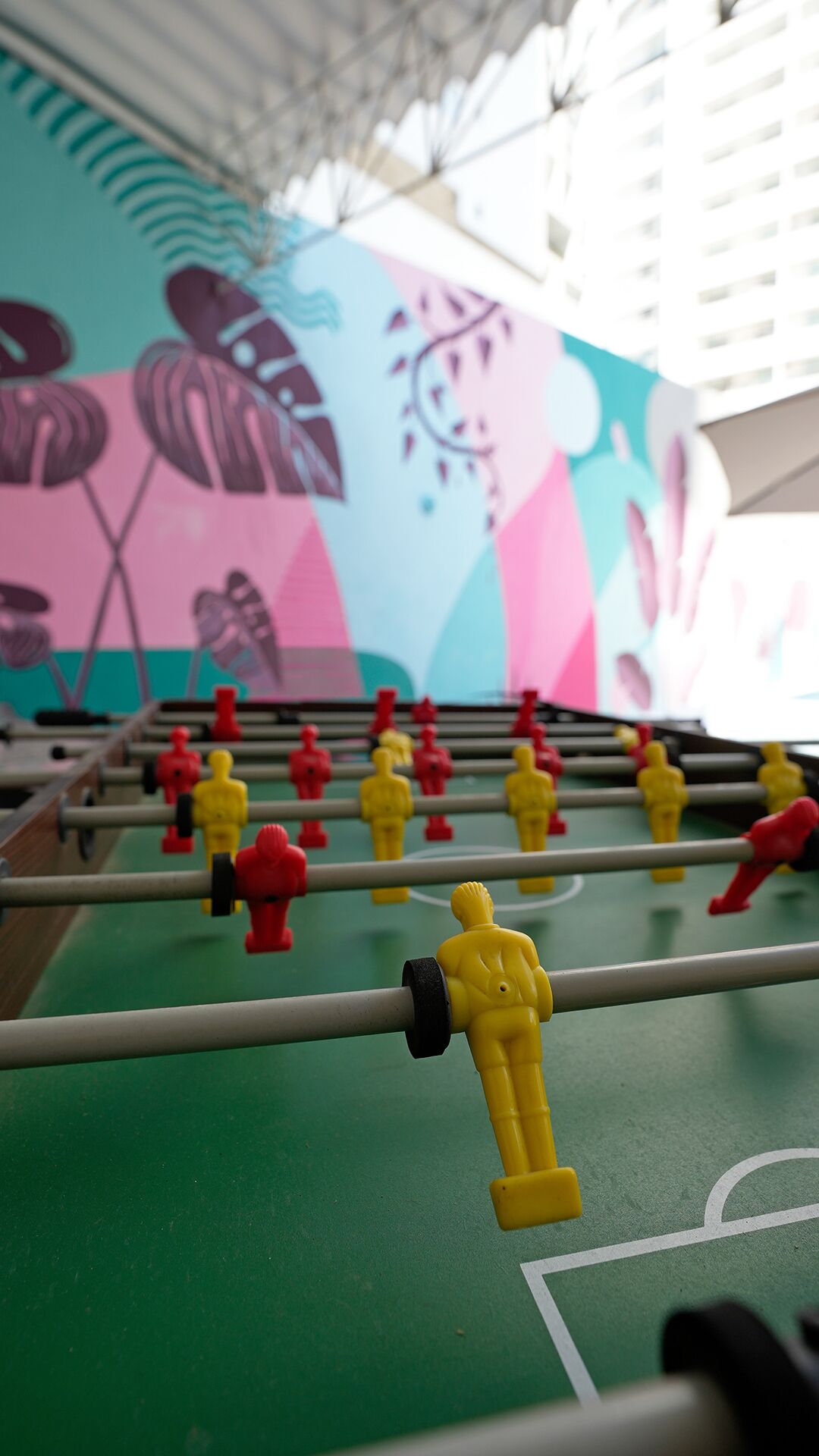 A foosball table with a colorful mural in the background.