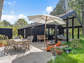 A modern outdoor patio area with a dining set, lounge chairs, and a covered seating area. - 5 Star Holiday Home in Hojby (Hojby)