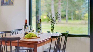 Une table à manger avec une bouteille de vin, des verres et un bol de raisins.
