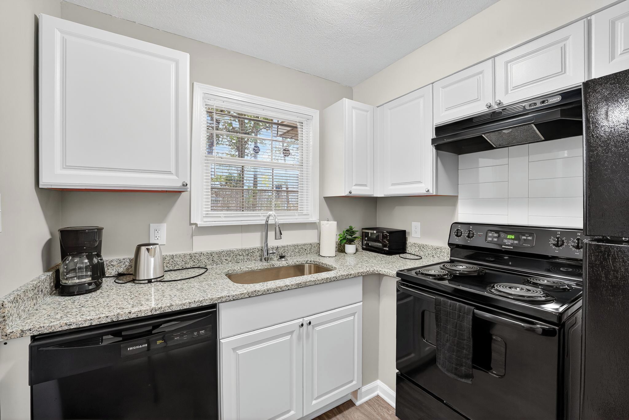 A kitchen with white cabinets, a black stove, and a granite countertop.