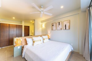 Une chambre d’hôtel avec un grand lit, un ventilateur de plafond, des lampes fixées au mur et des œuvres d’art.