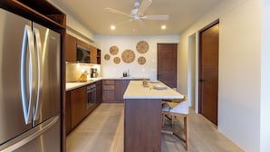 Een moderne keuken met een inbouwkoelkast, houten kastjes, een centraal eiland en decoratieve wanddecoraties.