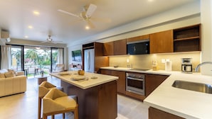 Een moderne keuken met een centraal eiland, inbouwapparatuur en een groot raam met uitzicht op een tuin.