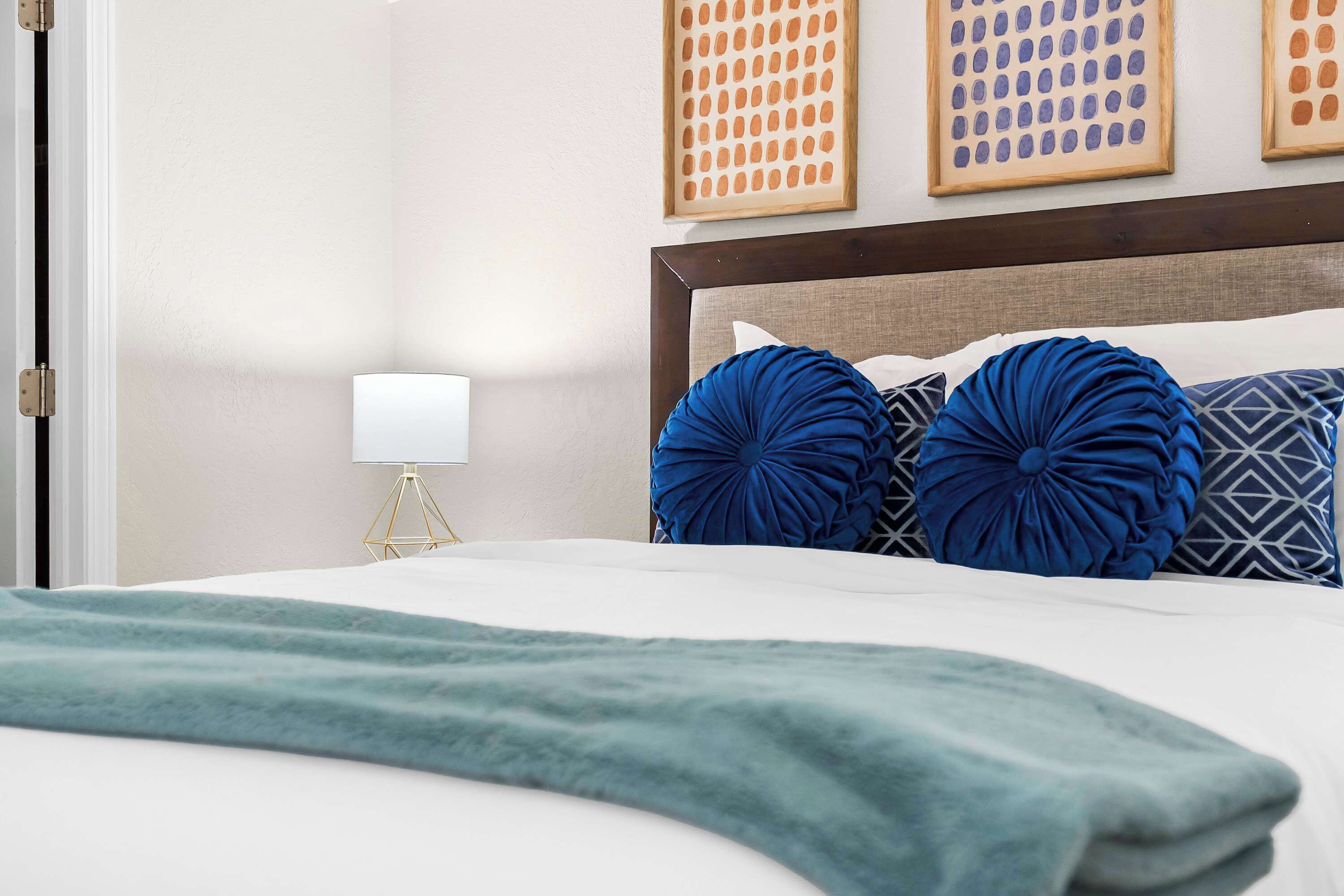 Una cama bien hecha con una manta verde, un cabecero de madera y almohadas decorativas.