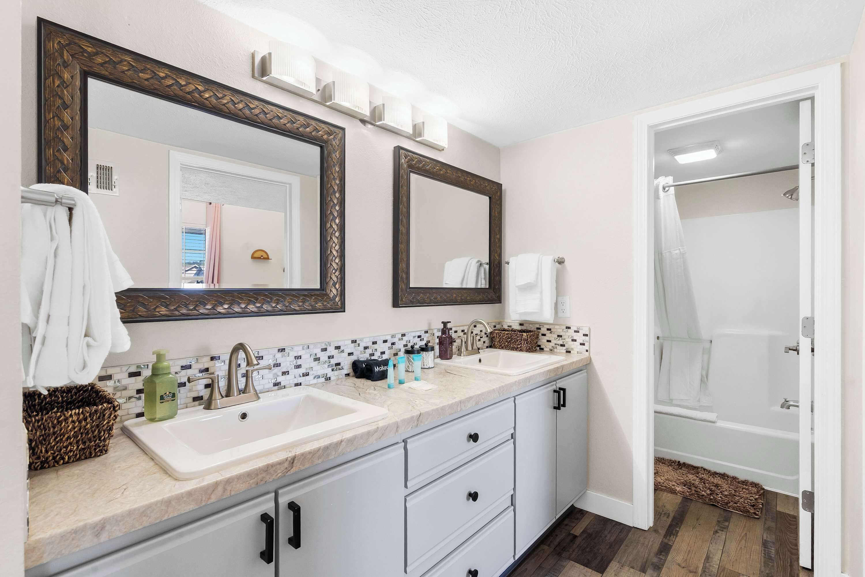 Une salle de bain avec deux lavabos, un miroir et une douche.