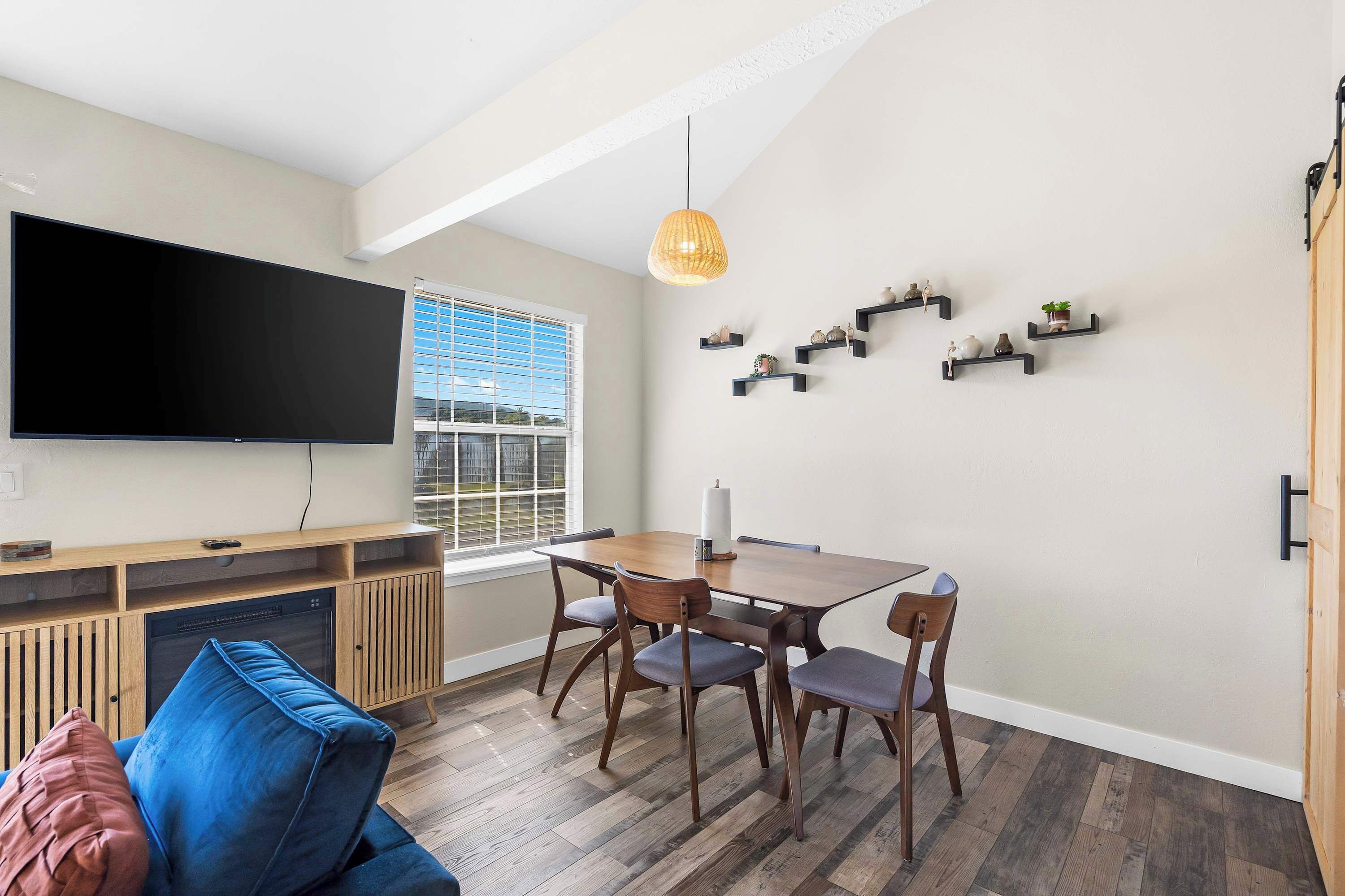 Una sala de estar moderna con televisor de pantalla plana, mesa de comedor de madera y sillas.