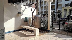 A courtyard with a bench, a large water tank, and a gated entrance with a parked car. - Chiang Mai Oasis 2-bedroom Home With Private Entrance & Modern Amenities (Chiang Mai)