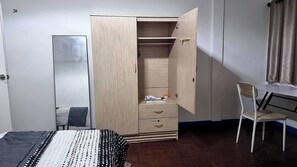 A bedroom with a wooden wardrobe, a bed with a patterned bedspread, a desk with a chair, and a mirror. - Chiang Mai Oasis 2-bedroom Home With Private Entrance & Modern Amenities (Chiang Mai)