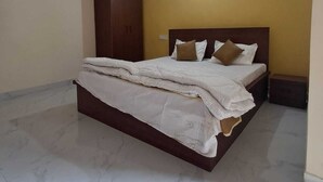 A bedroom with a bed, a ceiling fan, a wardrobe, and a nightstand. - Keshav Inn Hotel And Banquet (Ranchi)