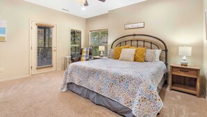 A bedroom with a bed, a ceiling fan, a nightstand, and a window with blinds. - The Fairway Getaway For 6 (Branson West)