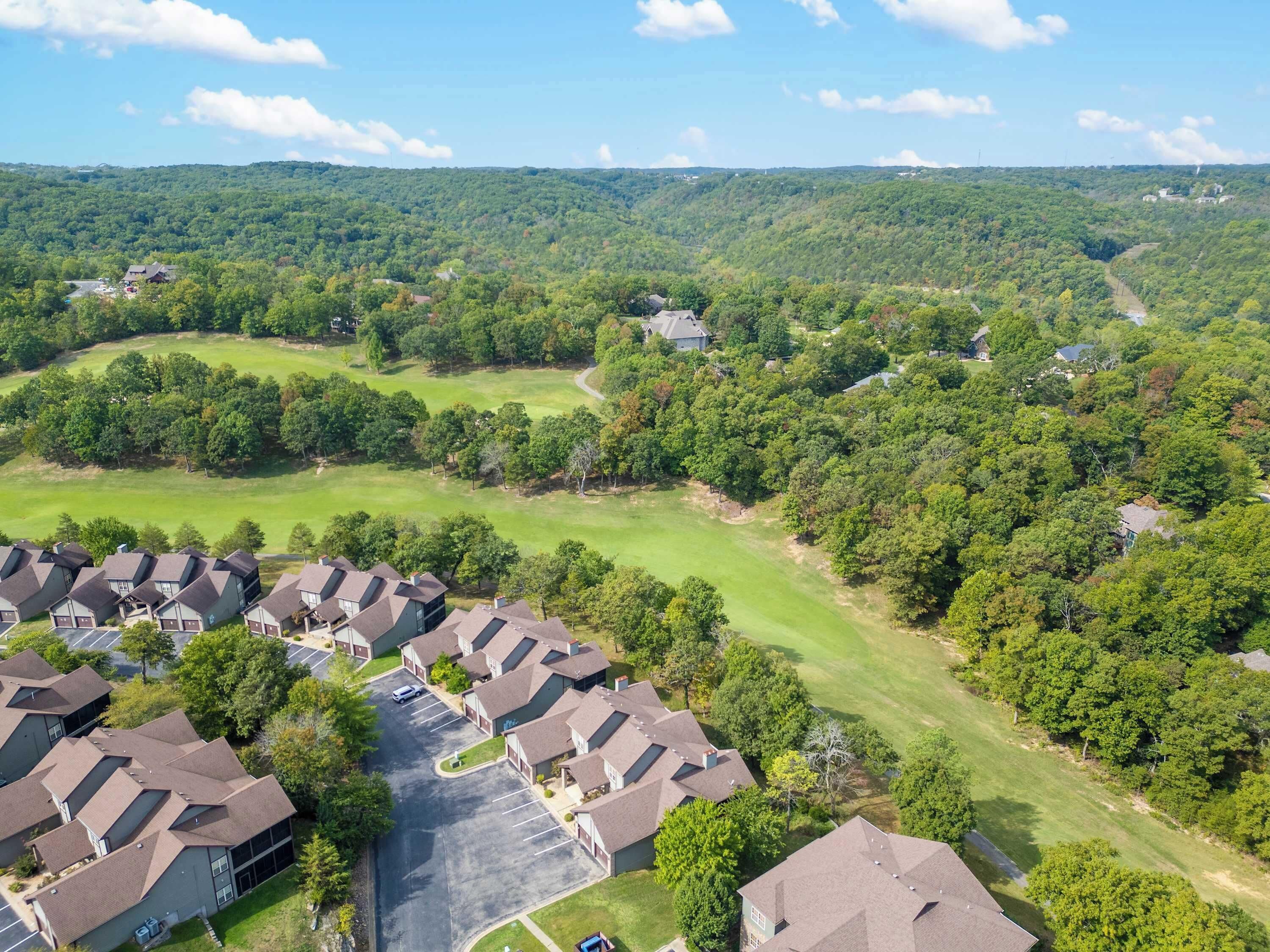 A residential area with houses, a golf course, and a parking lot.