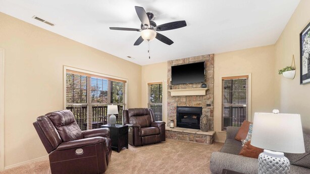 A living room with a fireplace, leather recliners, a TV, and a ceiling fan. - The Fairway Getaway For 6 (Branson West)