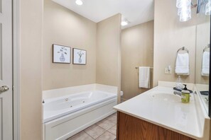 Une salle de bain moderne avec une grande baignoire, un lavabo et deux tableaux encadrés accrochés au mur.