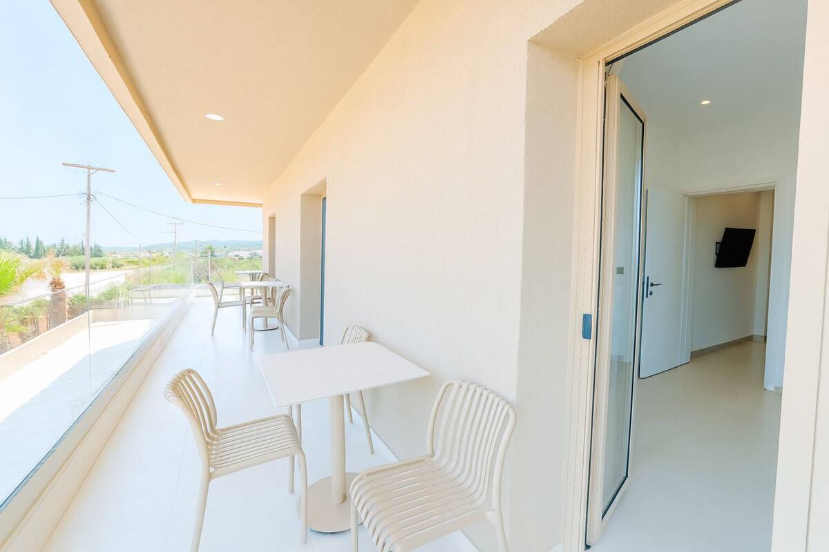 Een modern, minimalistisch balkon met witte meubels en uitzicht op het landschap.