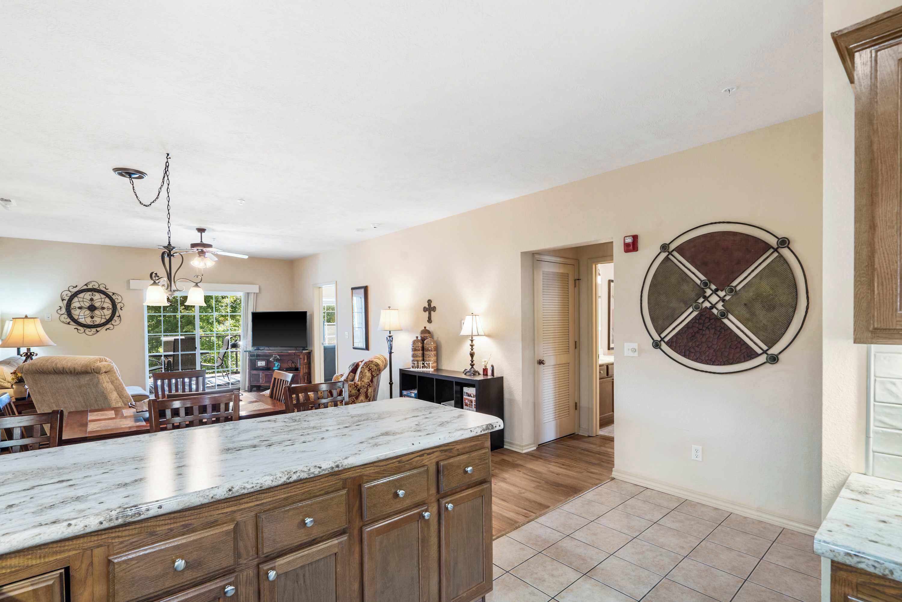A spacious kitchen with a large island, wooden cabinets, and a ceiling fan.