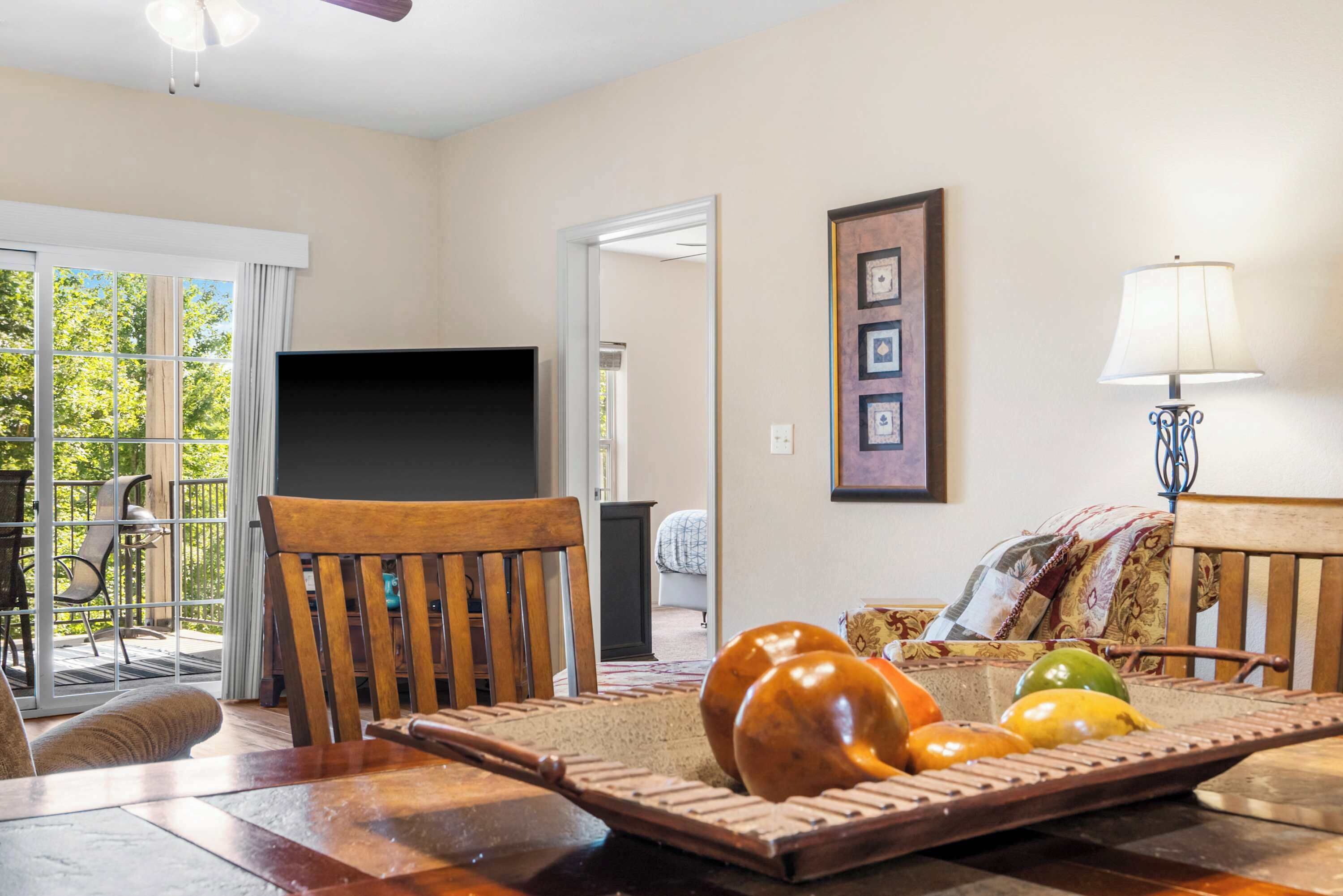 A living room with a wooden table, chairs, a television, and a framed picture on the wall.