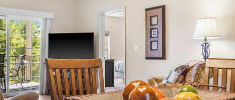 A living room with a wooden table, chairs, a television, and a framed picture on the wall.