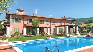 Ein großes Gebäude mit Swimmingpool, grünen Rollläden und einem gepflegten Rasen.