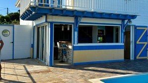 Ein zweigeschossiges Gebäude mit Balkon, Pool und überdachter Terrasse.