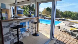 Eine moderne Küche mit Poolbar, großem Fenster und Blick auf den Pool.