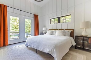 Une chambre à coucher avec un grand lit, une table de chevet, une fenêtre avec des rideaux et une vue sur la verdure.