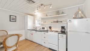 Une cuisine avec des meubles blancs, une table à manger en bois et un réfrigérateur blanc.