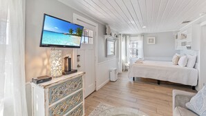Une chambre à coucher avec un lit, un téléviseur fixé au mur, une commode et une fenêtre.