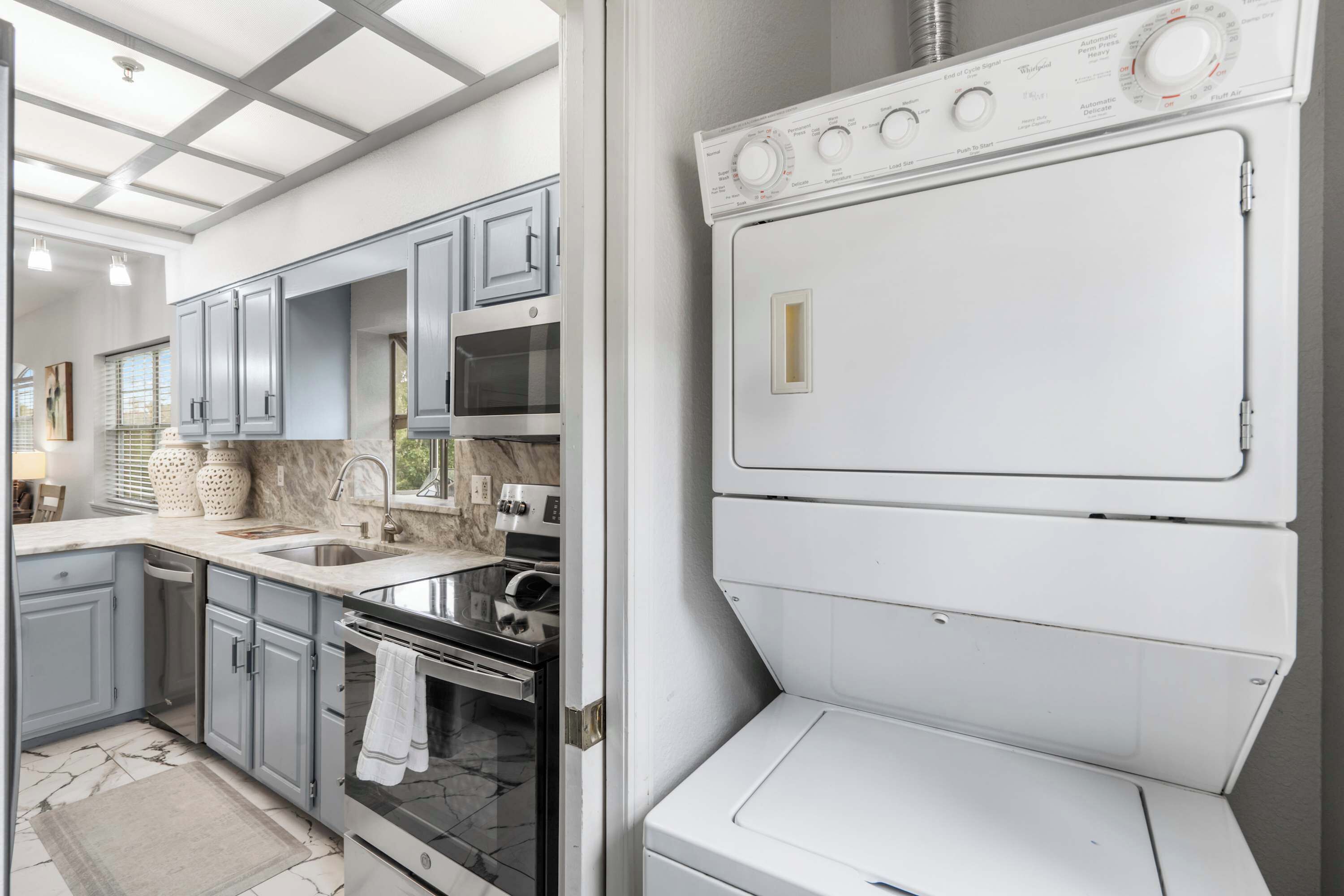 A compact kitchen with grey cabinets, a built-in oven, and a white washing machine.