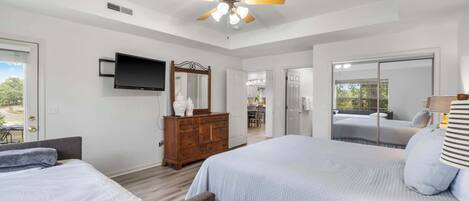 A bedroom with a bed, a dresser, a television, and a ceiling fan.