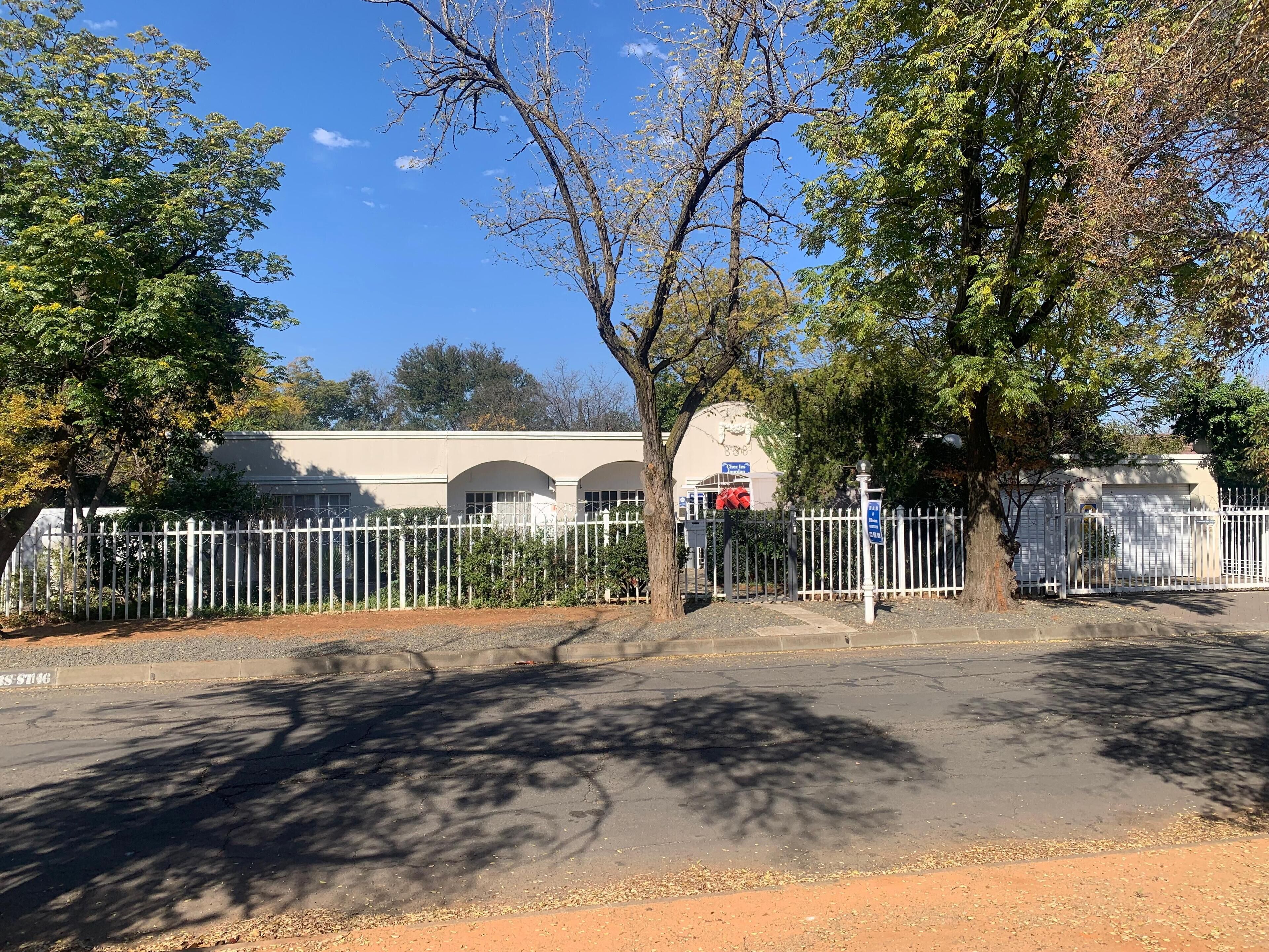 A fenced area with a building featuring arched windows and a signboard.