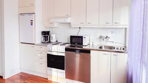 A compact kitchen with white cabinets, a stainless steel dishwasher, a coffee maker, and a microwave.