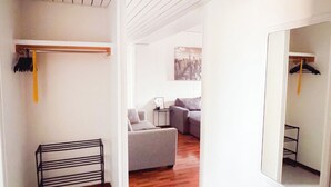 A modern interior with a wooden floor, a grey sofa, and a white wall with a mirror.