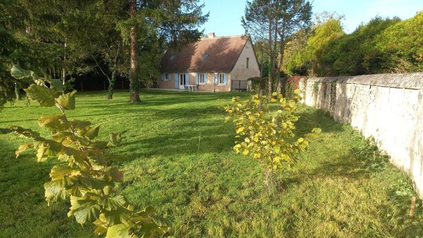A house with a sloped roof, a well-maintained lawn, and a stone wall. - Gîte du Moulin de Chanvre with Private Terrace and Garden (Preuilly-sur-Claise)