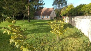 A house with a sloped roof, a well-maintained lawn, and a stone wall. - Gîte du Moulin de Chanvre with Private Terrace and Garden (Preuilly-sur-Claise)