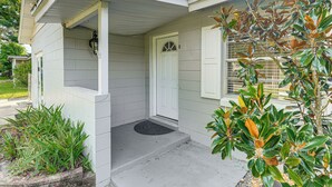 A house with a front porch, a door, and a small garden area with plants. - Gateway to Orlando Theme Parks! Home w/ Large Yard (Winter Park)