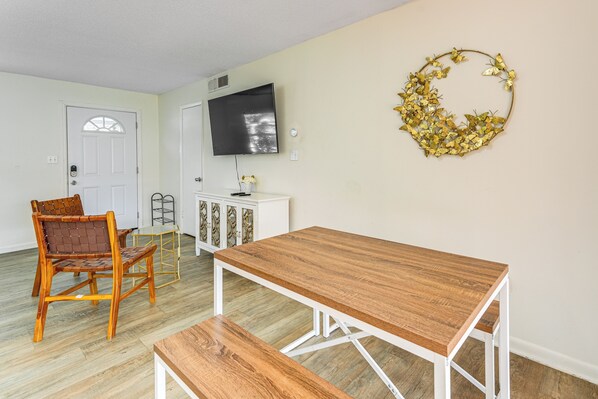 A dining area with a wooden table and bench, a white cabinet, a television, and a decorative wall piece. - Gateway to Orlando Theme Parks! Home w/ Large Yard (Winter Park)
