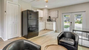 A modern kitchen with white cabinets, a black refrigerator, and a dining area with two leather chairs and a round table. - Townhome w/ Fenced Yard in Orlando Suburbs! (Winter Park)