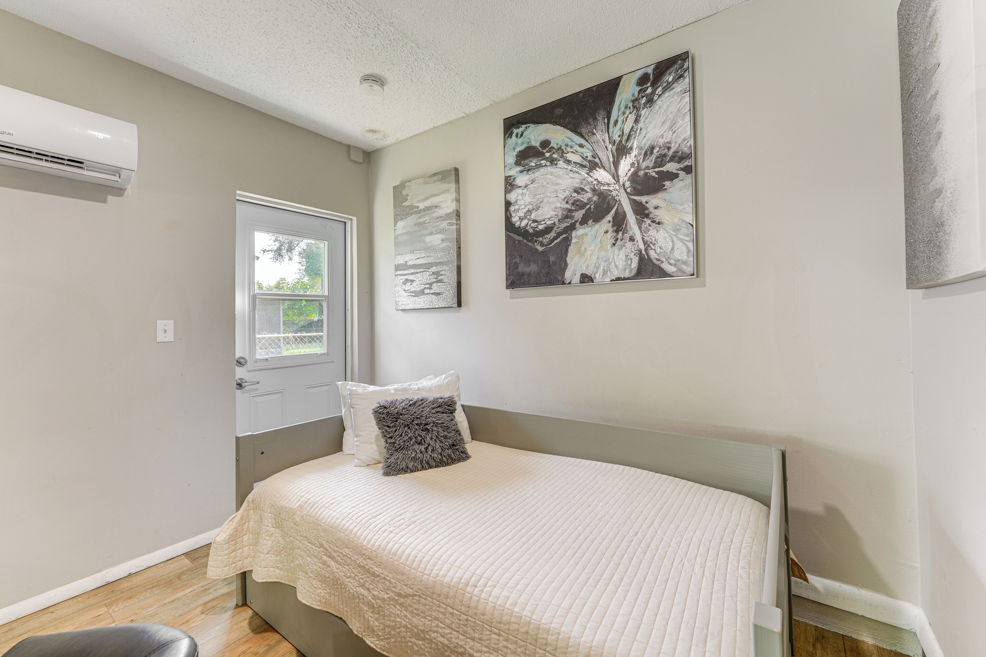 A bedroom with a bed, a window, and an air conditioning unit.