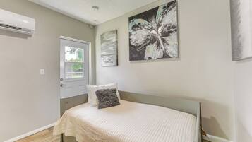 A bedroom with a bed, a window, and an air conditioning unit.