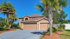 A two-story house with a garage, surrounded by palm trees and a well-maintained lawn. - Games, Bikes & Kids Play Area: Ocala Family Home (Ocala)